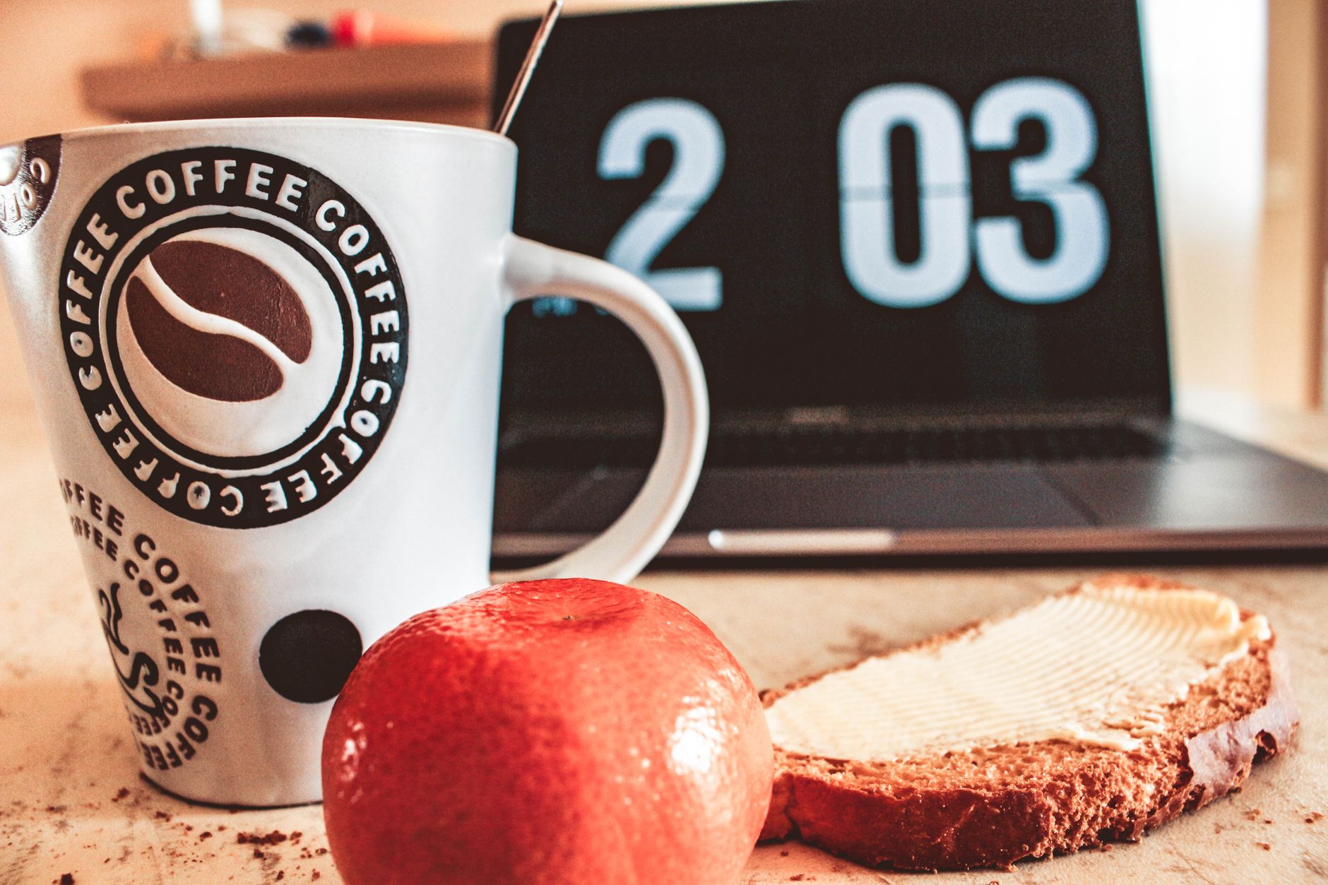 Un petit-déjeuner cosy avec café, pain et fruits à côté d'un ordinateur portable, symbole du travail depuis chez soi.